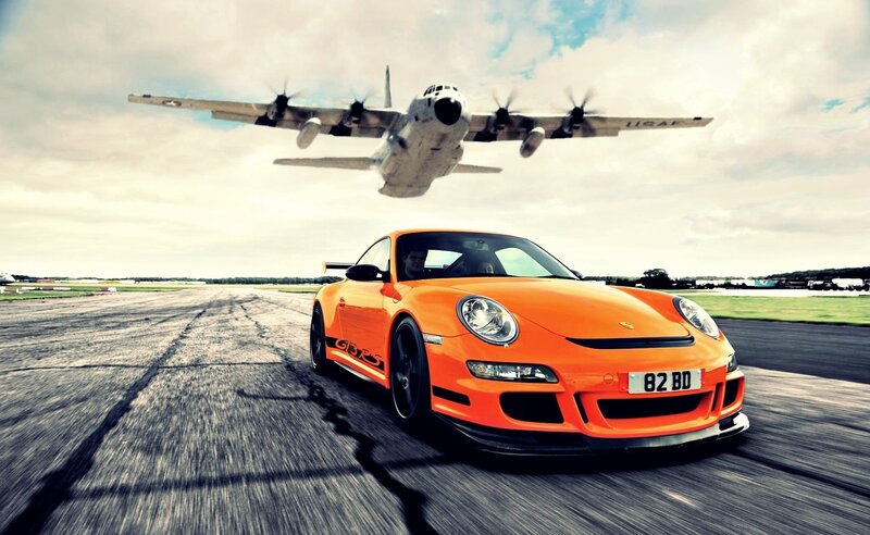 Orange Porsche on runway with plane