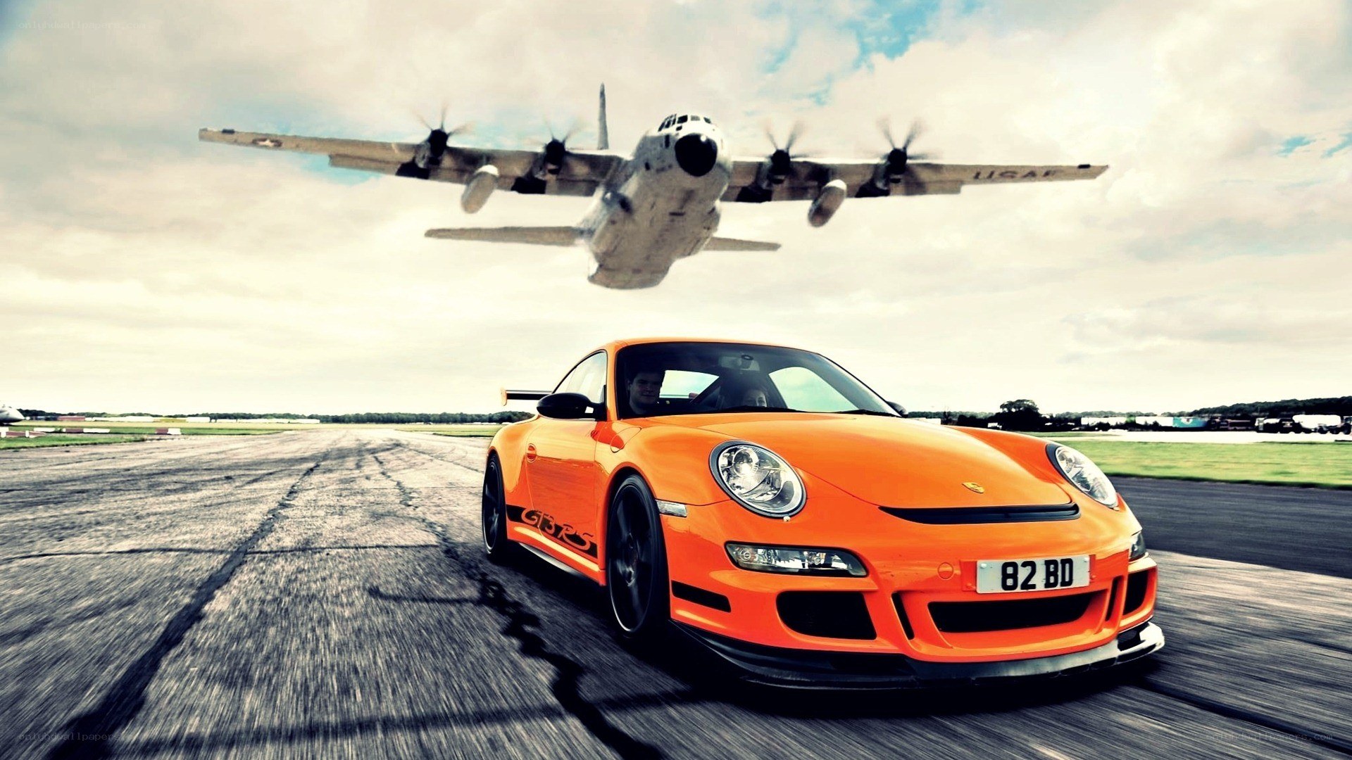 Orange Porsche on runway with plane