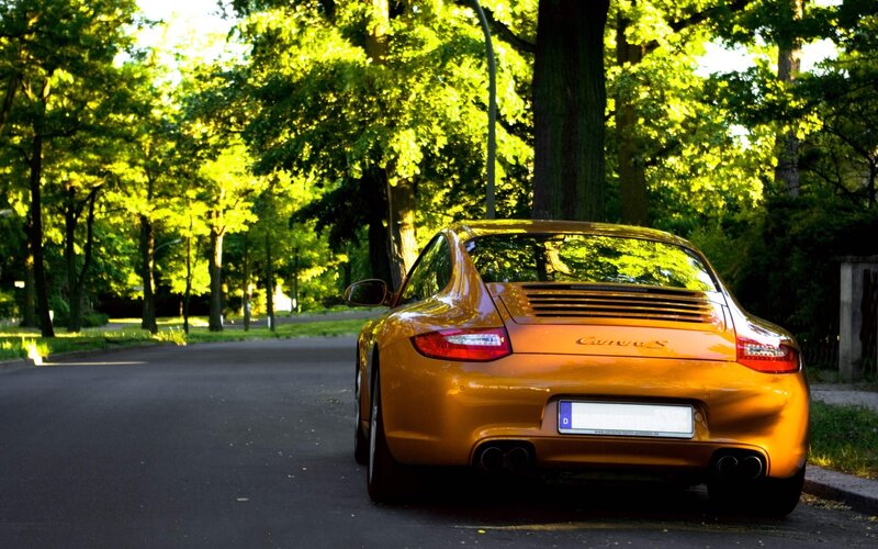 Orange Porsche parked on a tree-lined street