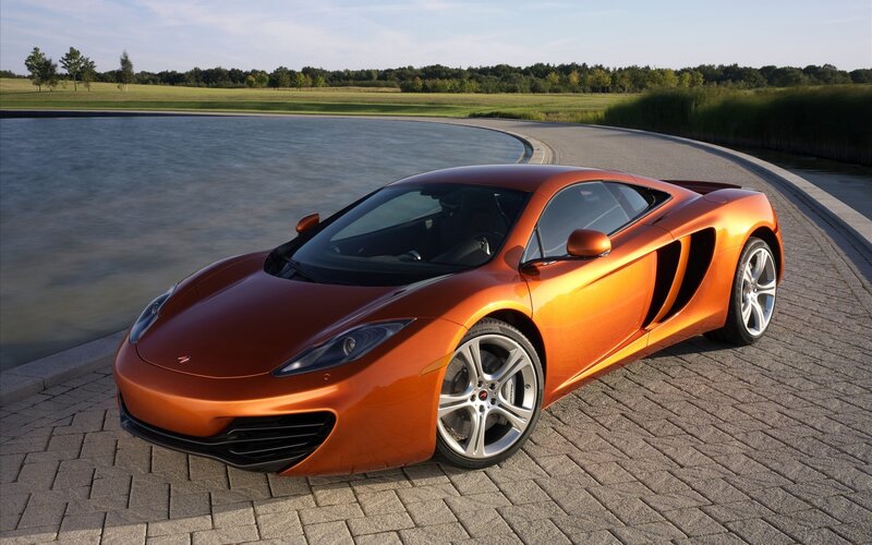 orange sports car by lake