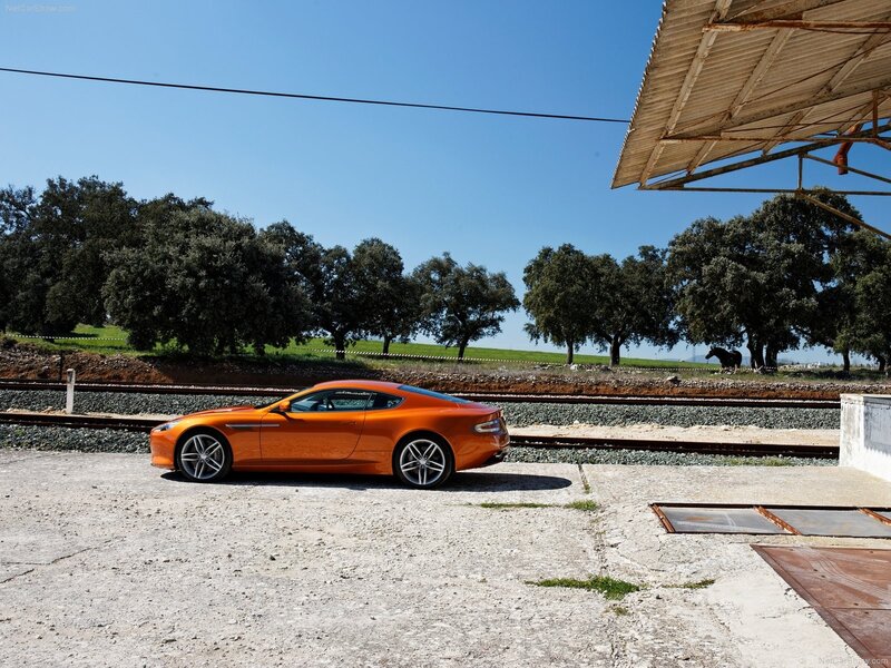 orange sports car by train tracks