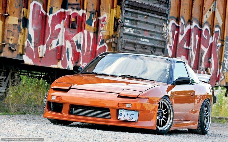Orange sports car near graffiti train