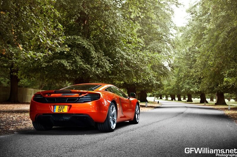 Orange sports car on a tree-lined road