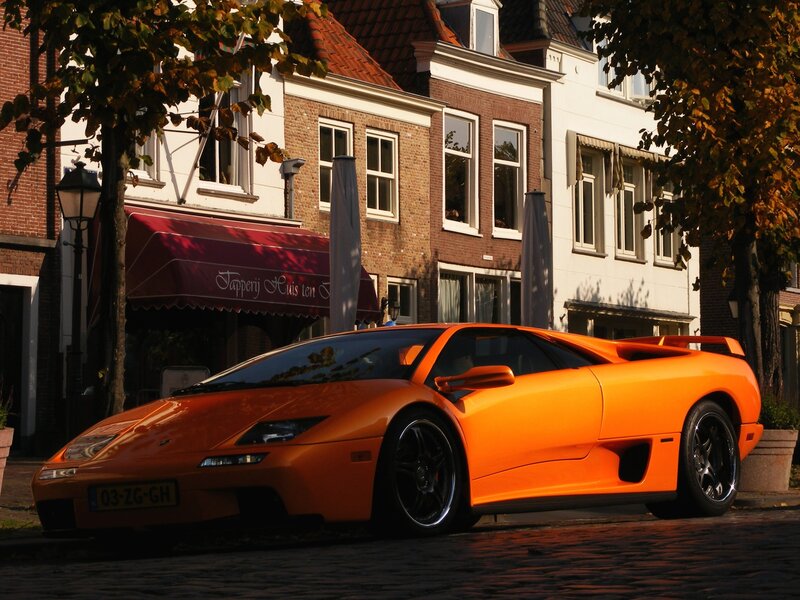 Orange sports car on cobblestone street