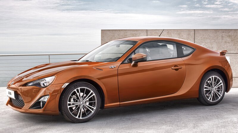Orange sports coupe by the sea