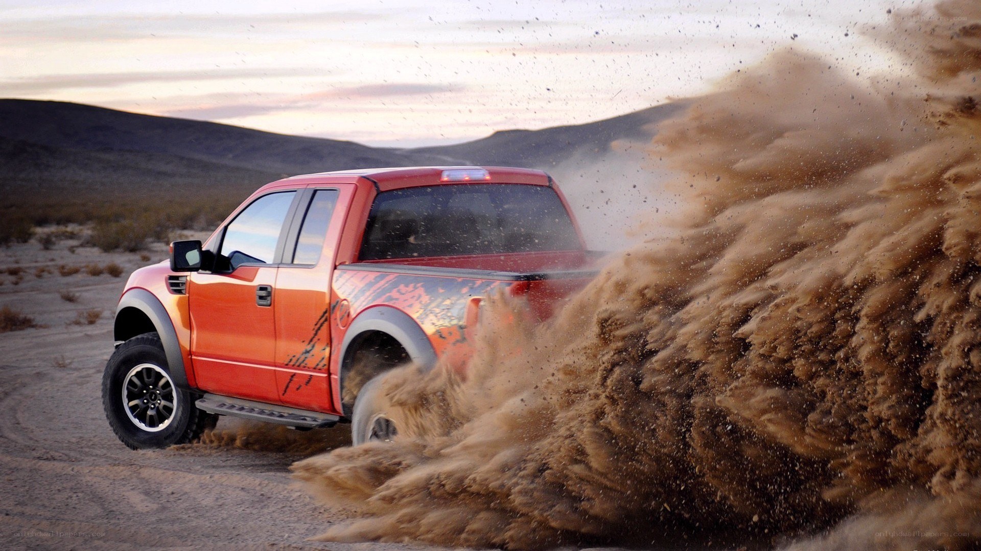 Orange truck kicking up dust