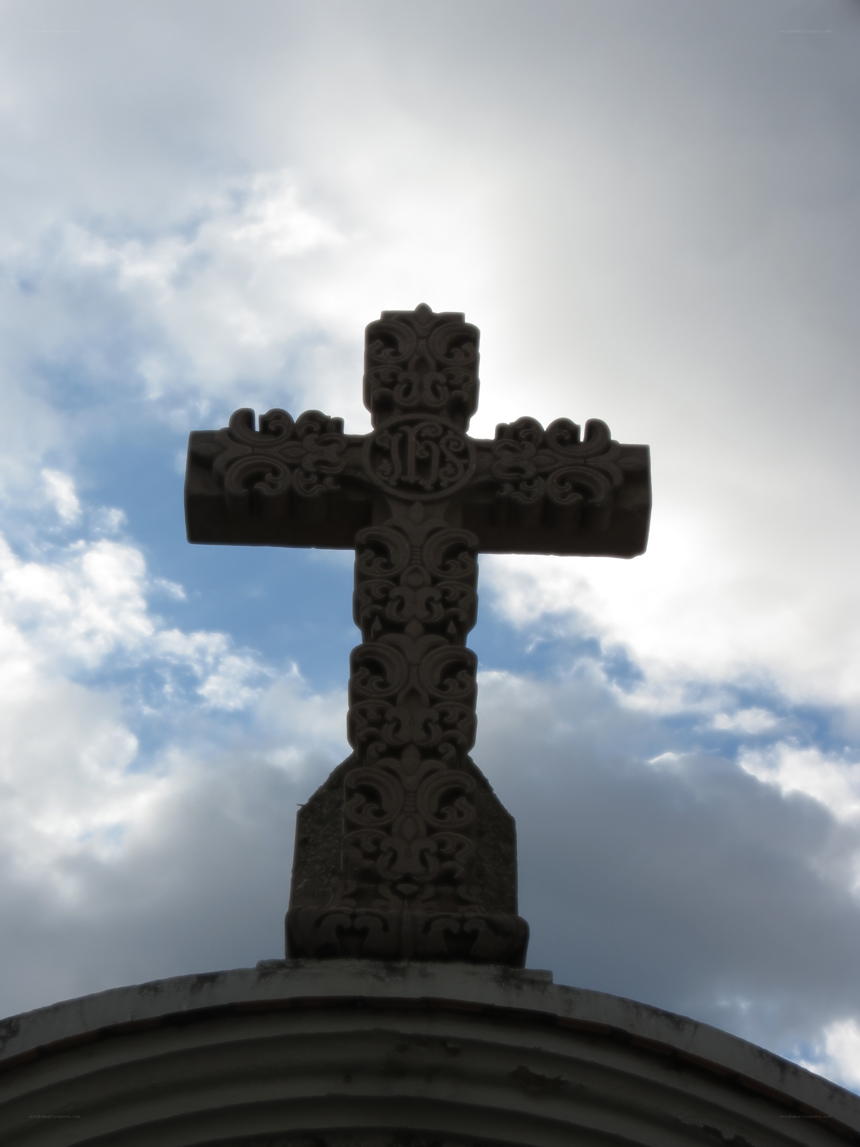 ornate cross against cloudy sky