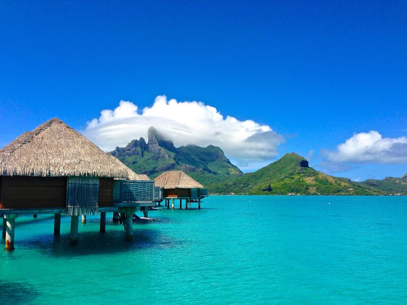 Overwater Bungalows — Blue, Serene, Afternoon, Photograph, Mountains, Thatched Roofs