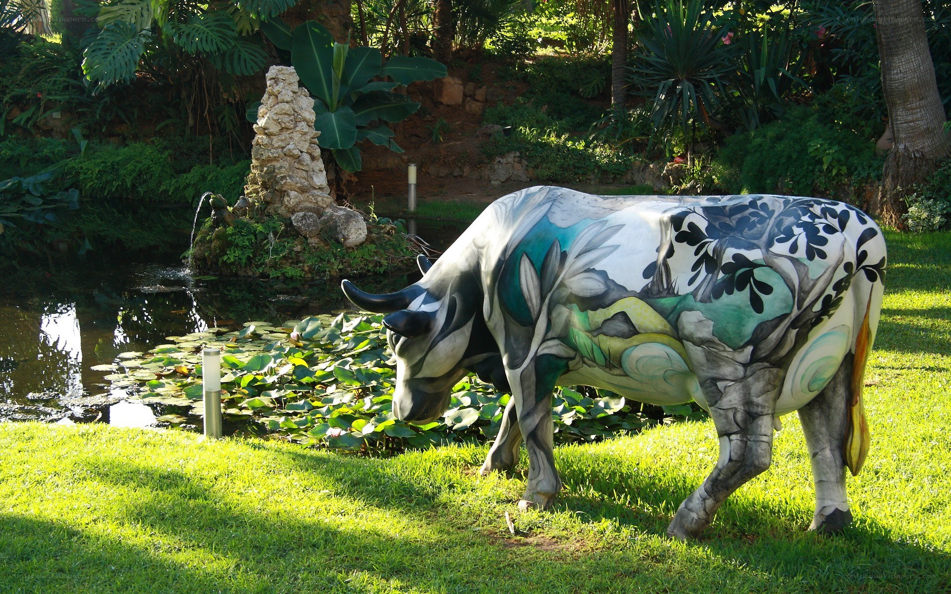 Painted cow statue by pond