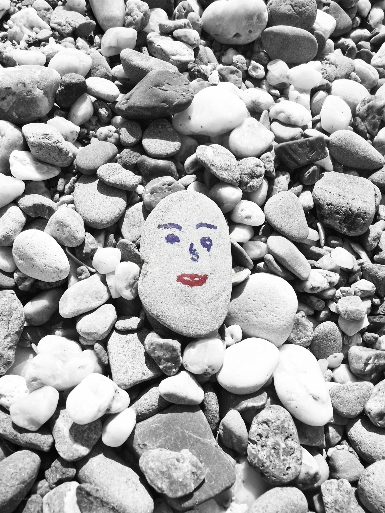 Painted face on a beach stone