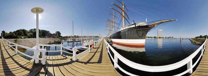 Panoramic view of a harbor with a tall ship