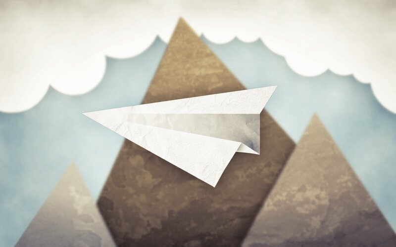 Paper airplane flying over mountains