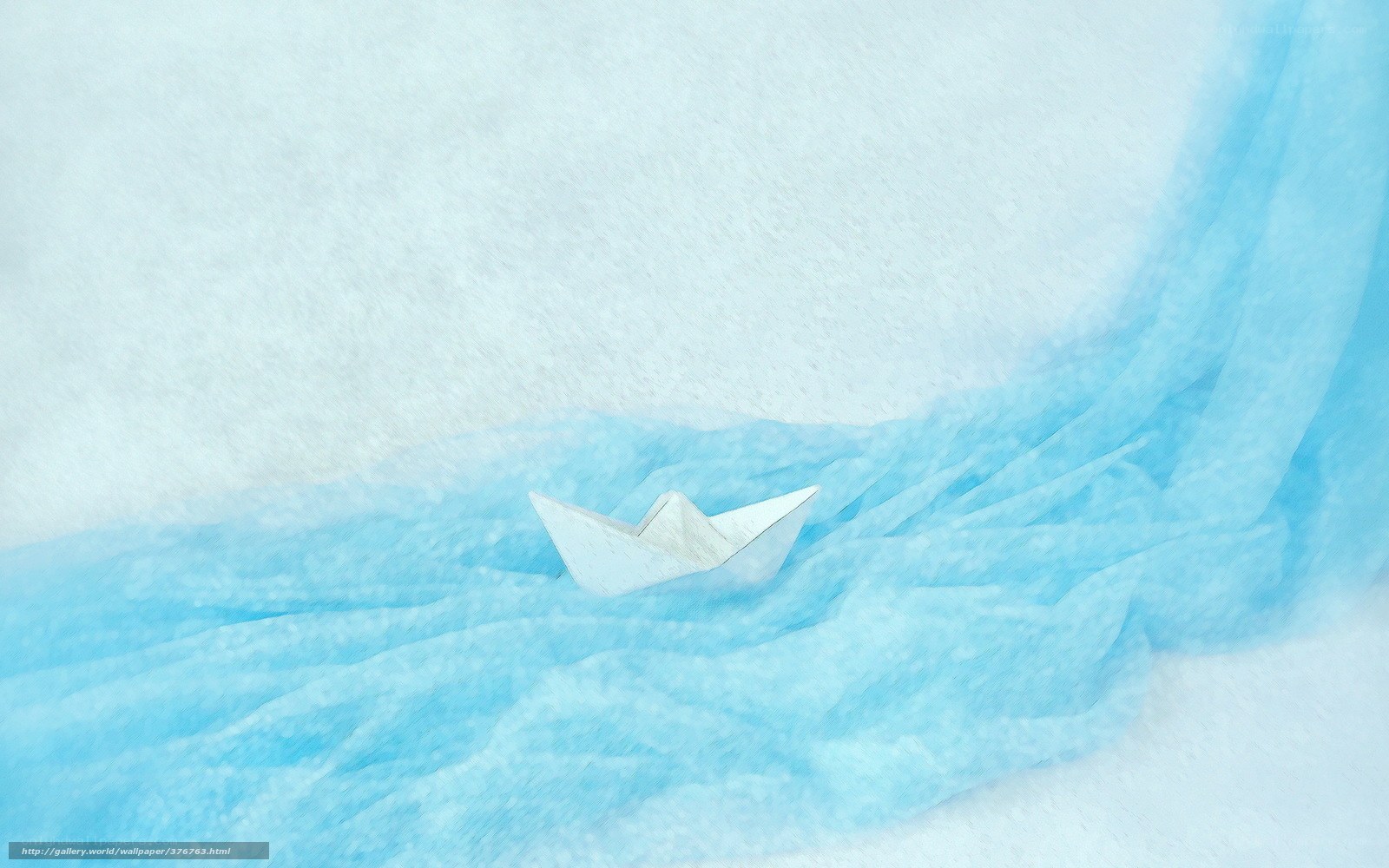 Paper boat on blue fabric
