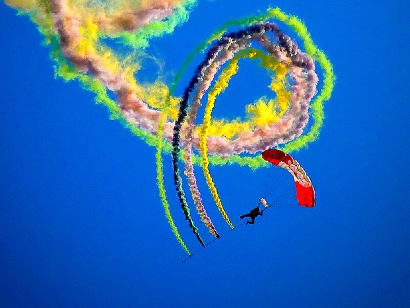 Parachutist with colorful smoke trails