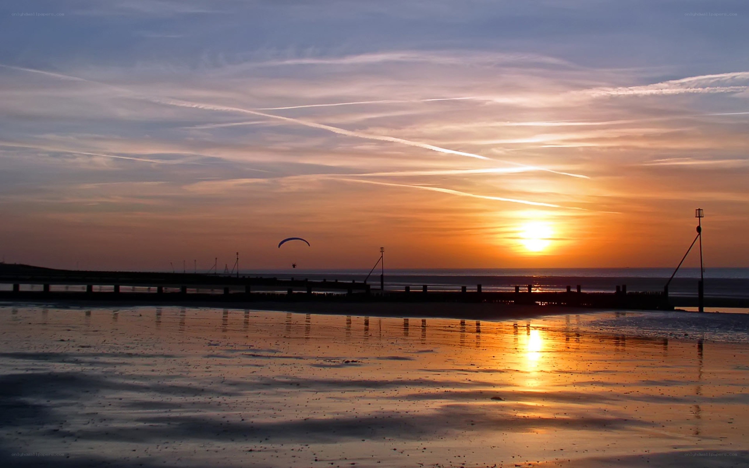 Paraglider at sunset over beach