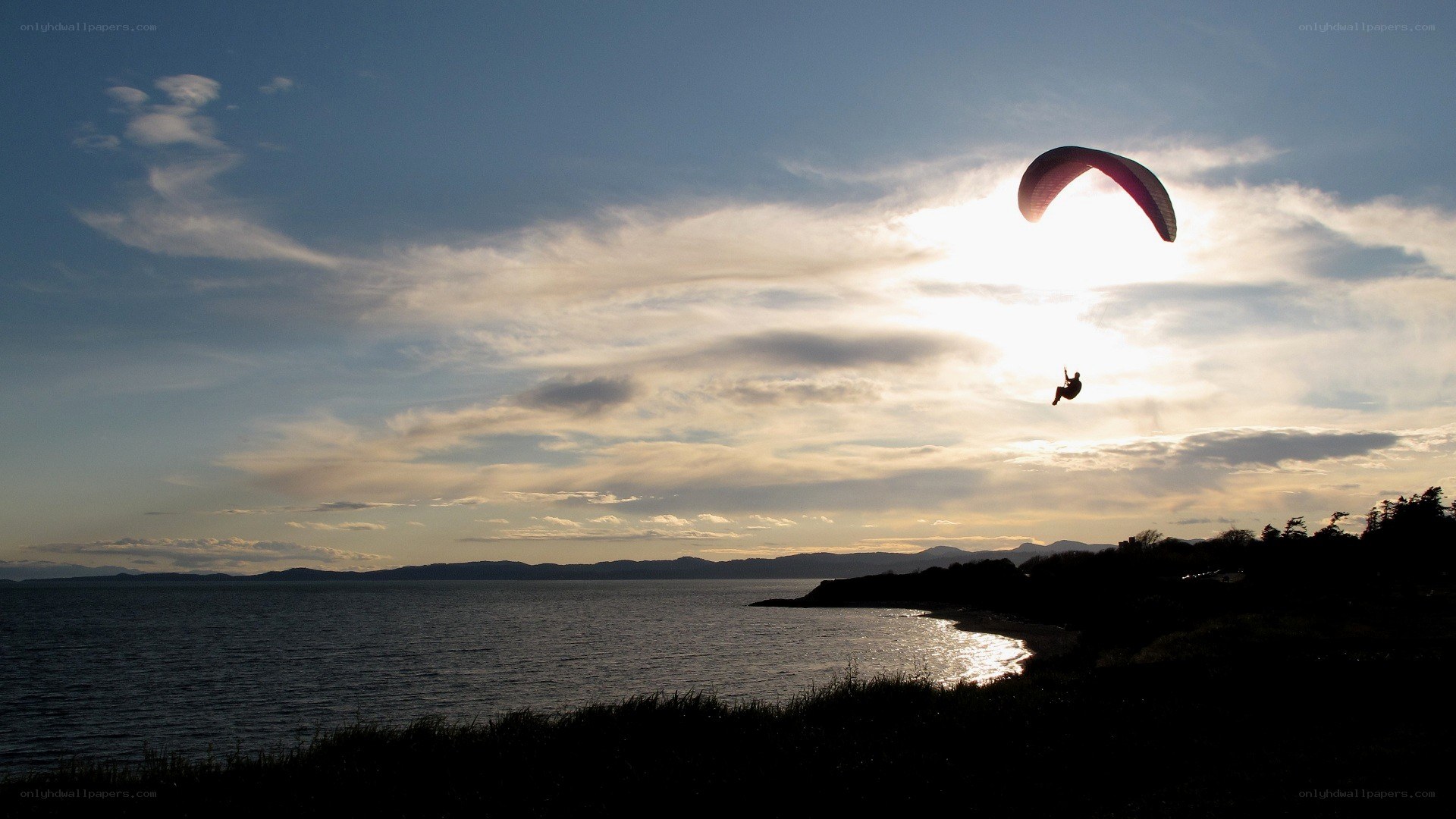 Paraglider at sunset over water
