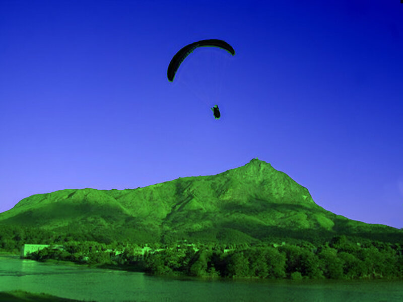 Paraglider over a green mountain