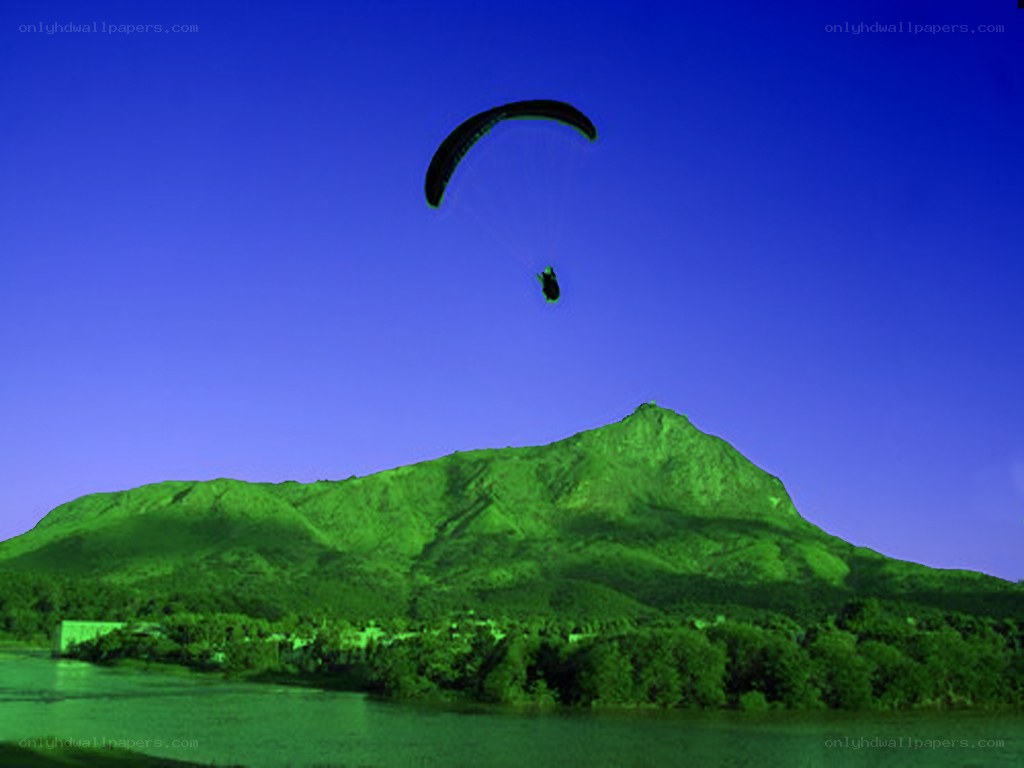 Paraglider over a green mountain