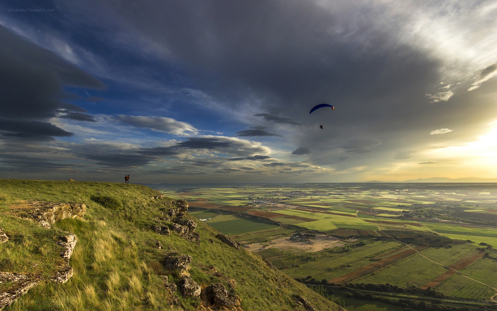 Paraglider over a valley at sunset