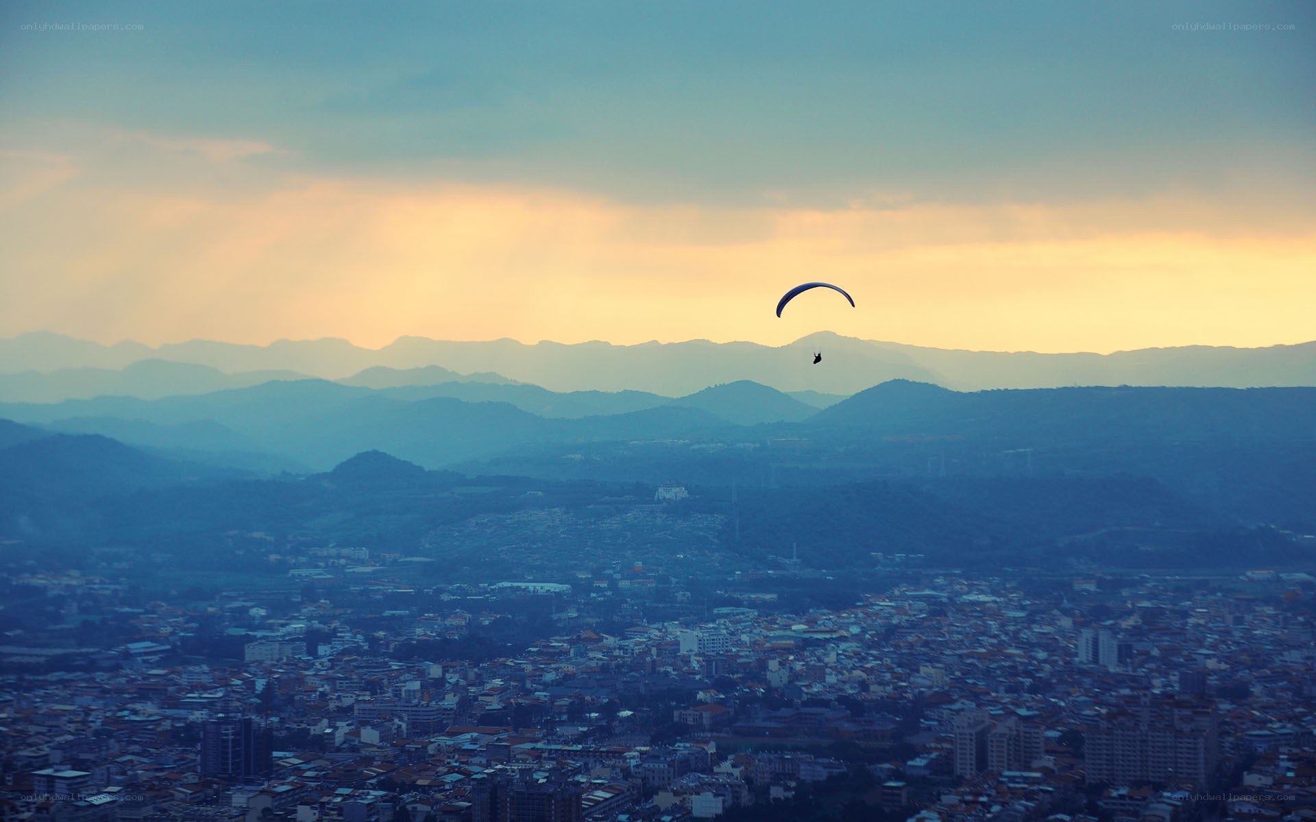 Paraglider over city at sunset