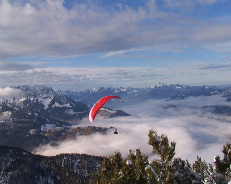 Paraglider over mountain clouds