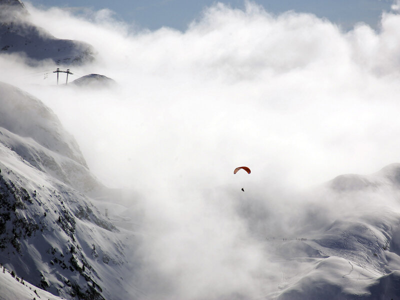 Paraglider over snowy mountains