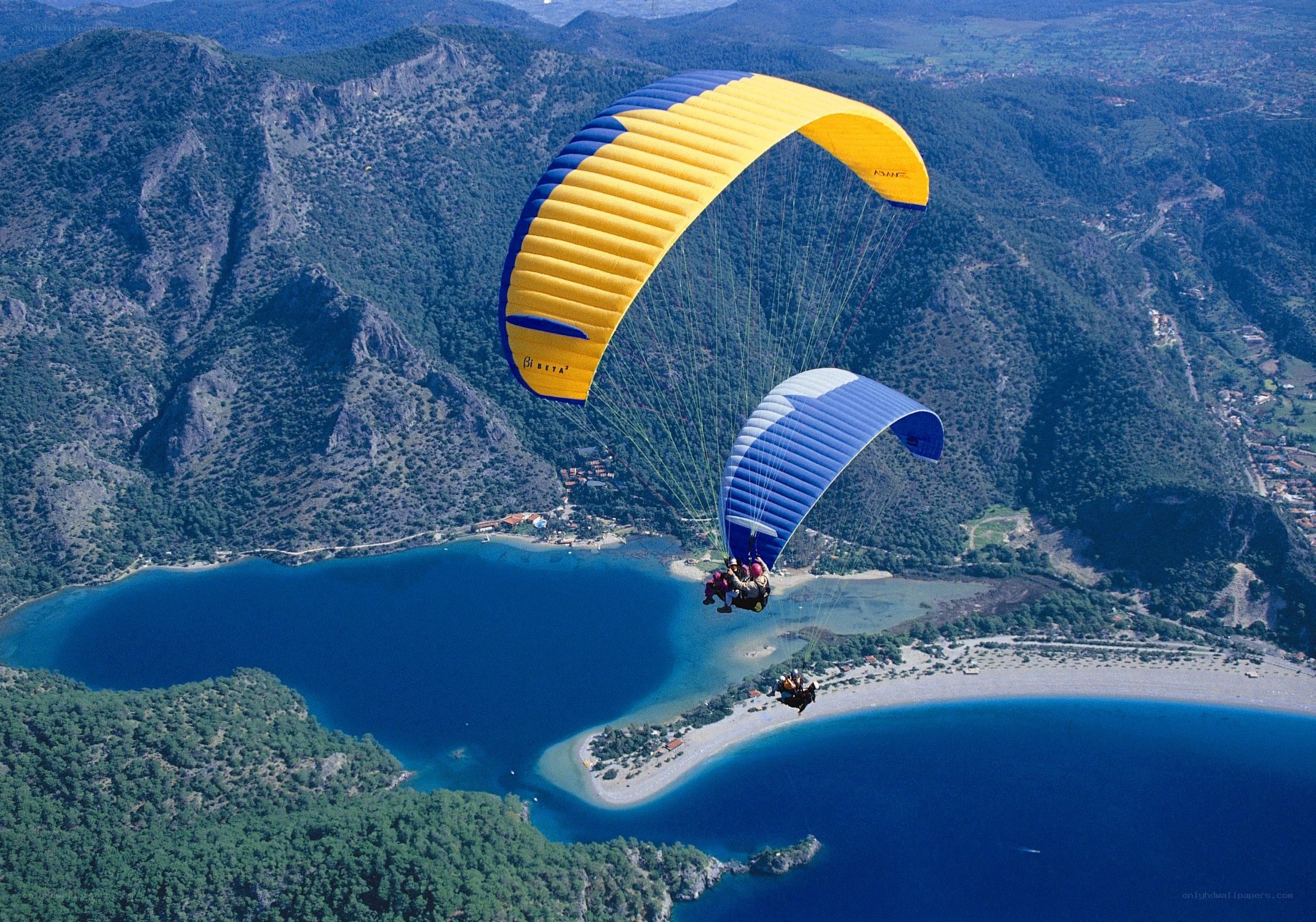 Paragliders over a coastal bay