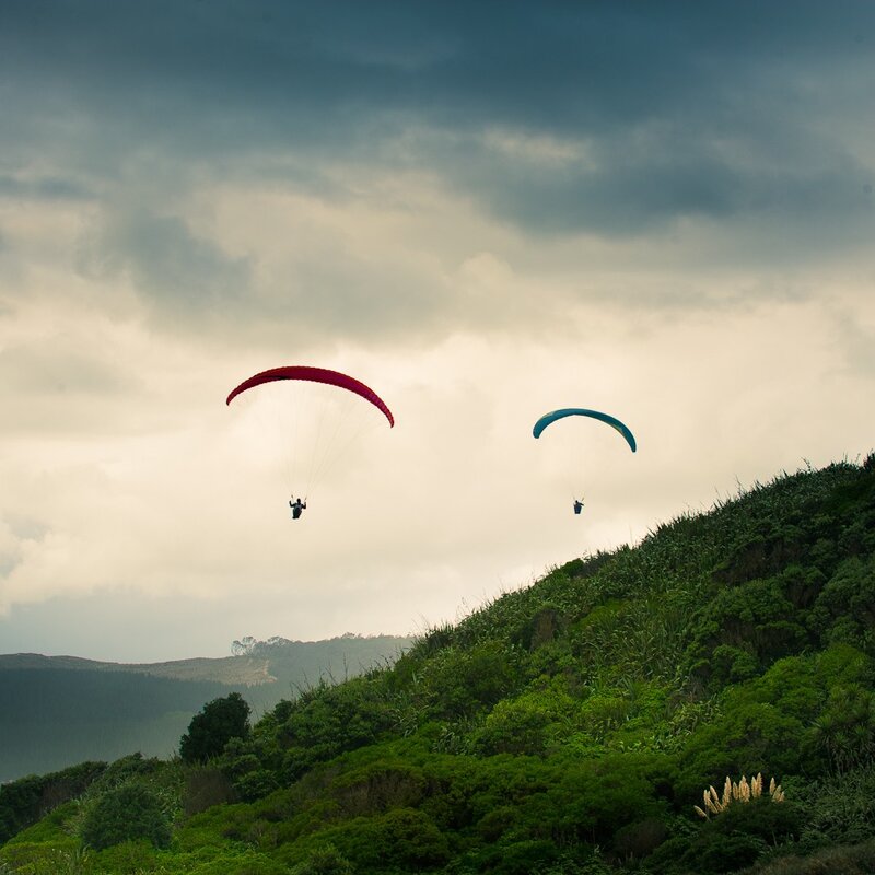 Paragliders over green hills