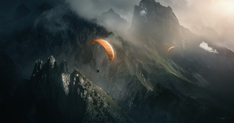 Paragliders over misty mountains