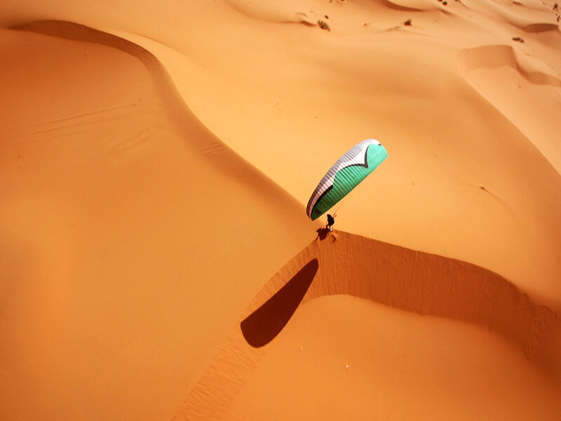 Paragliding over desert dunes