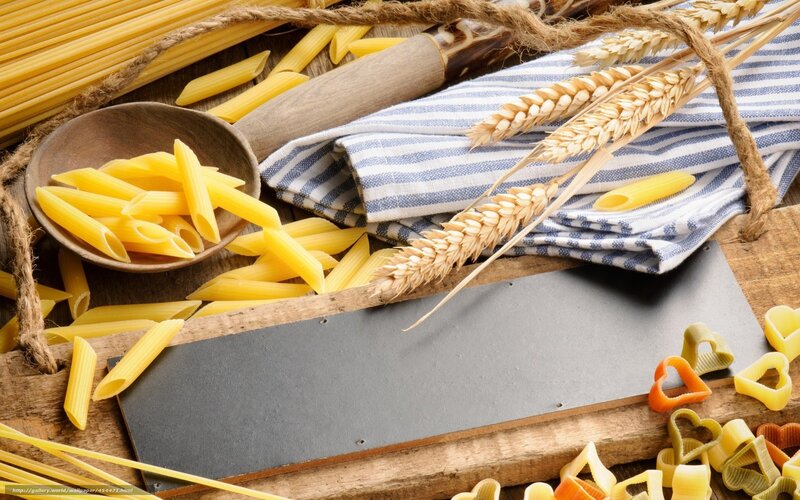 Pasta and wheat stalks on wood