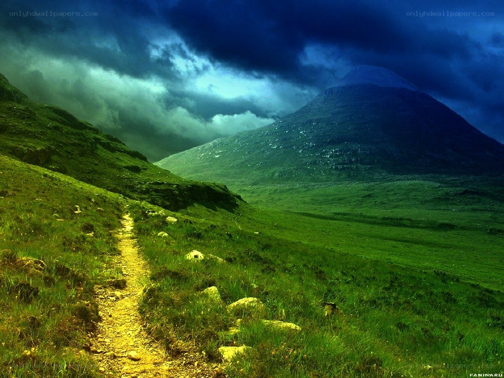 Path through green hills under stormy sky