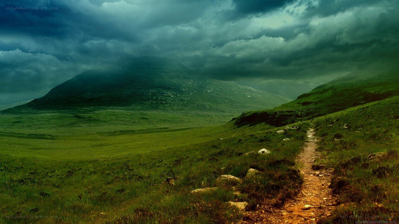 Path through green hills under stormy sky