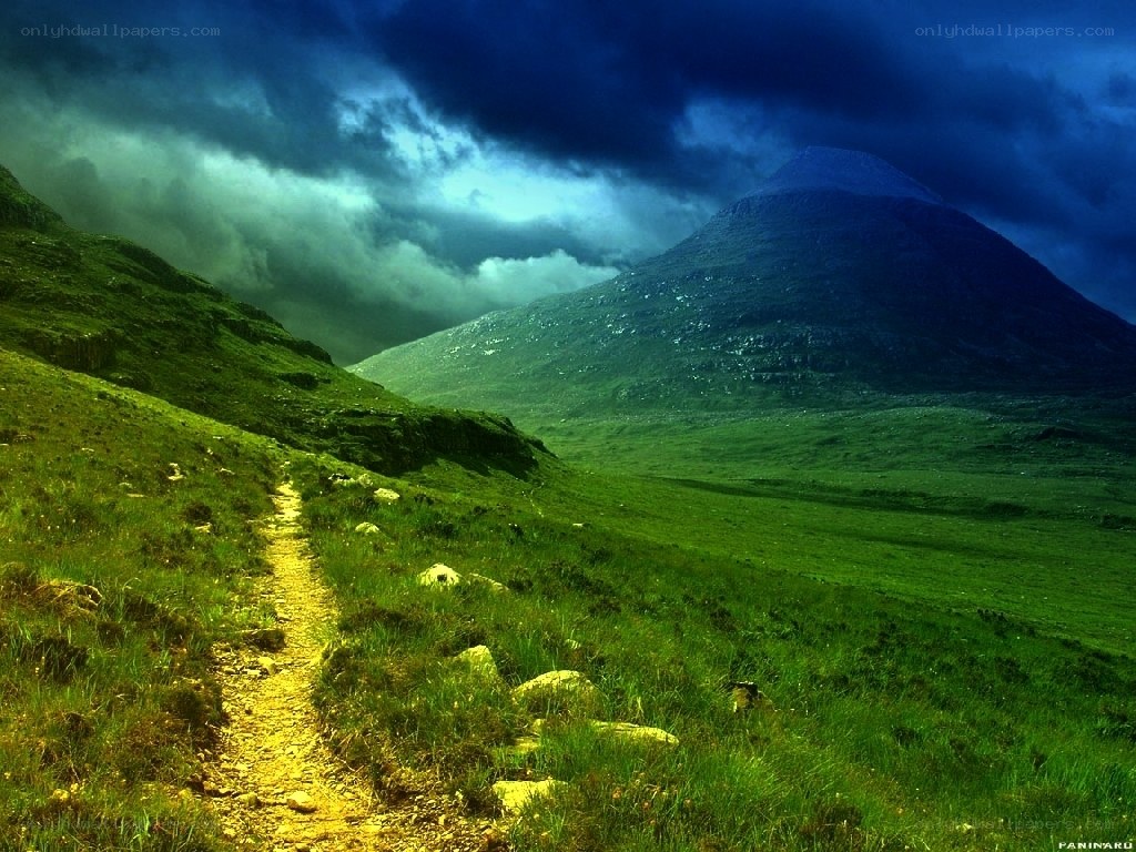Path through green hills under stormy sky