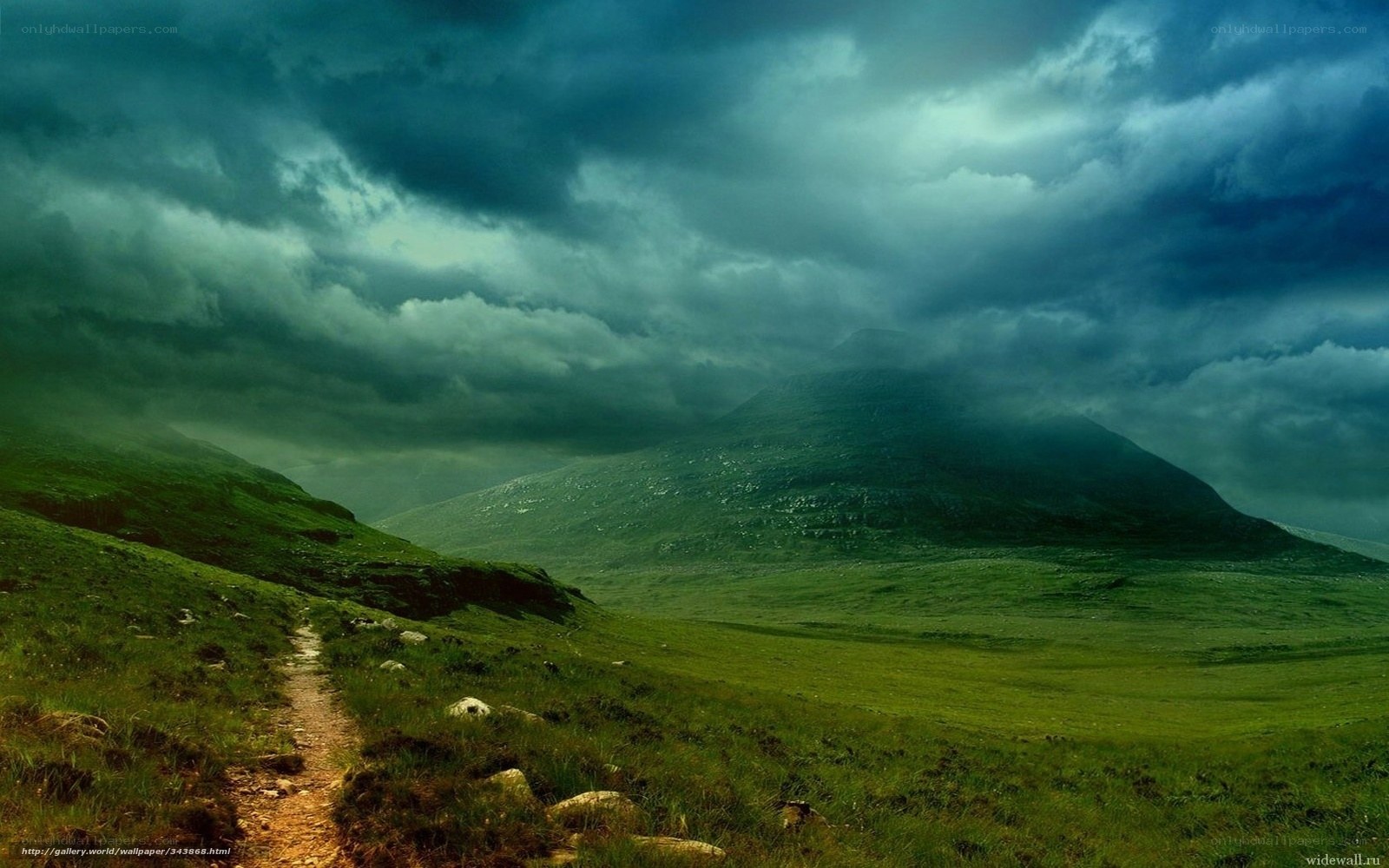 Path through green hills under stormy sky