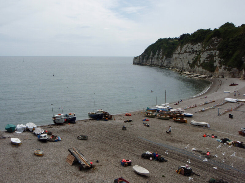 pebble beach with boats and cliffs
