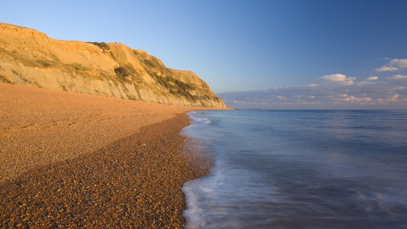 Pebble beach with cliffs at sunset