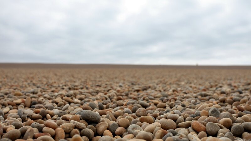 pebbled beach under cloudy sky