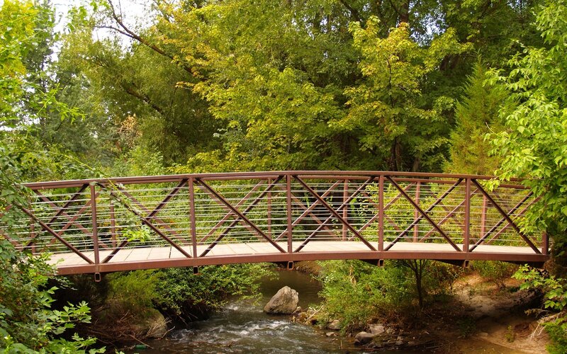 Pedestrian Bridge over Stream — Green, Serene, Afternoon