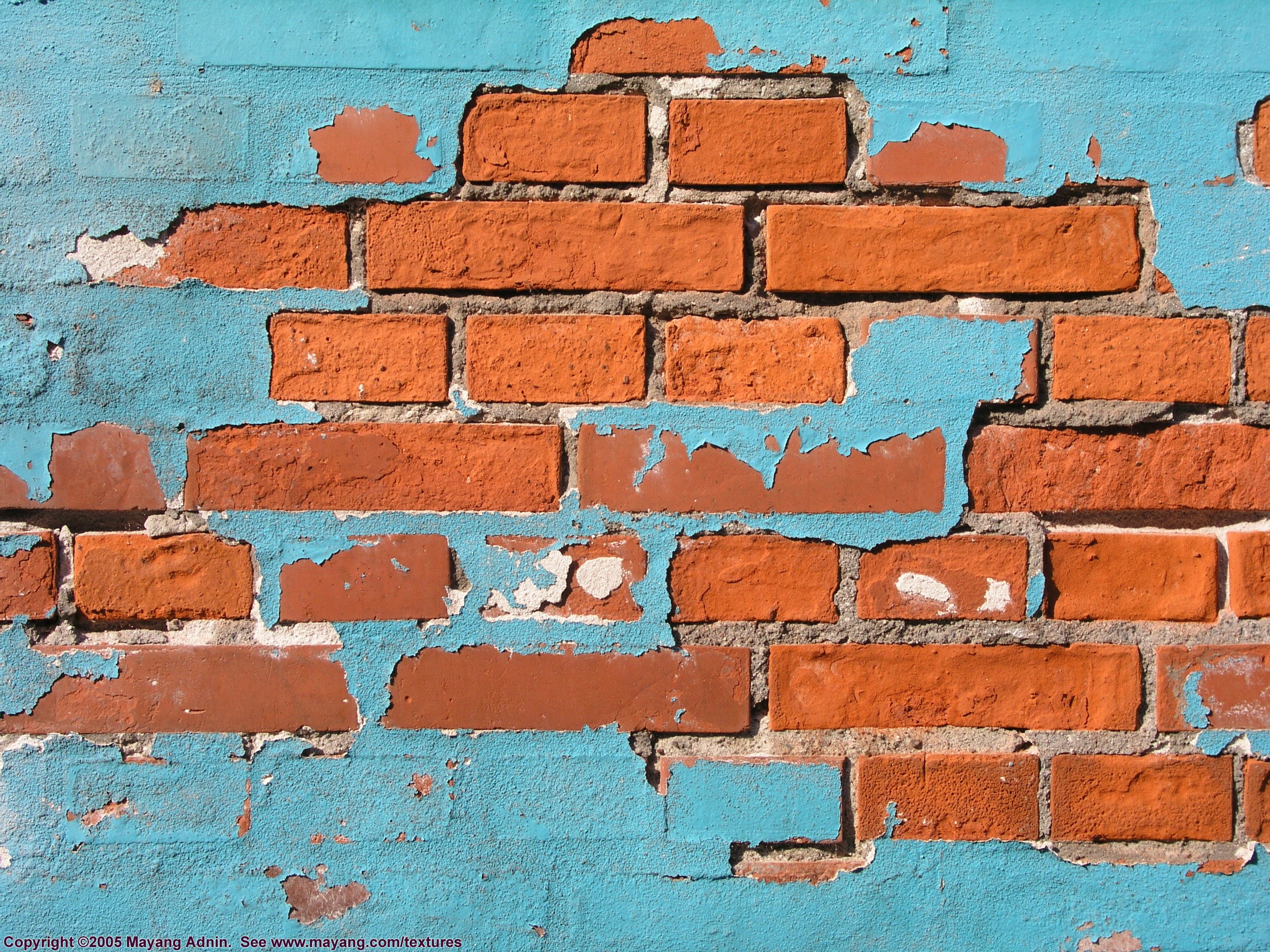 peeling blue paint on brick wall