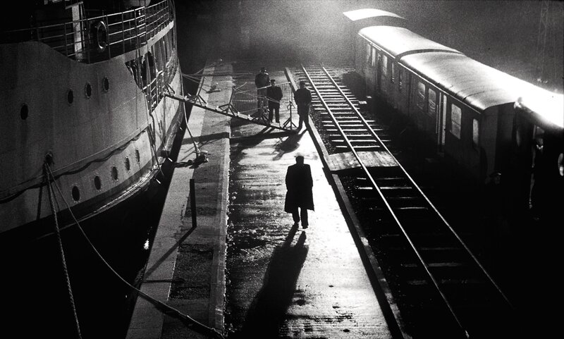People at a dock with boat and train