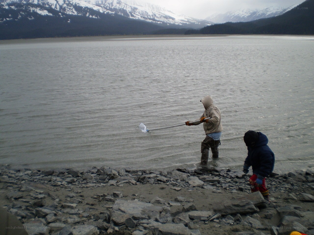 People at a lakeside with mountains