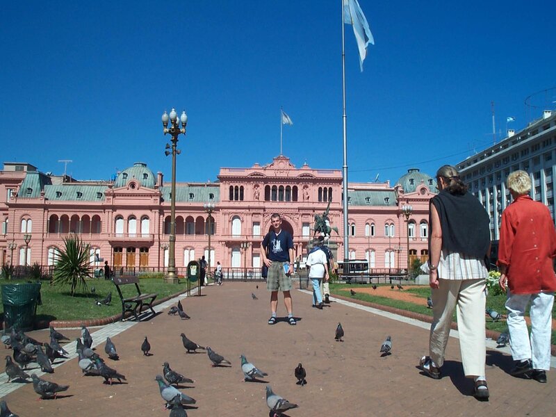 People at a plaza with pink building