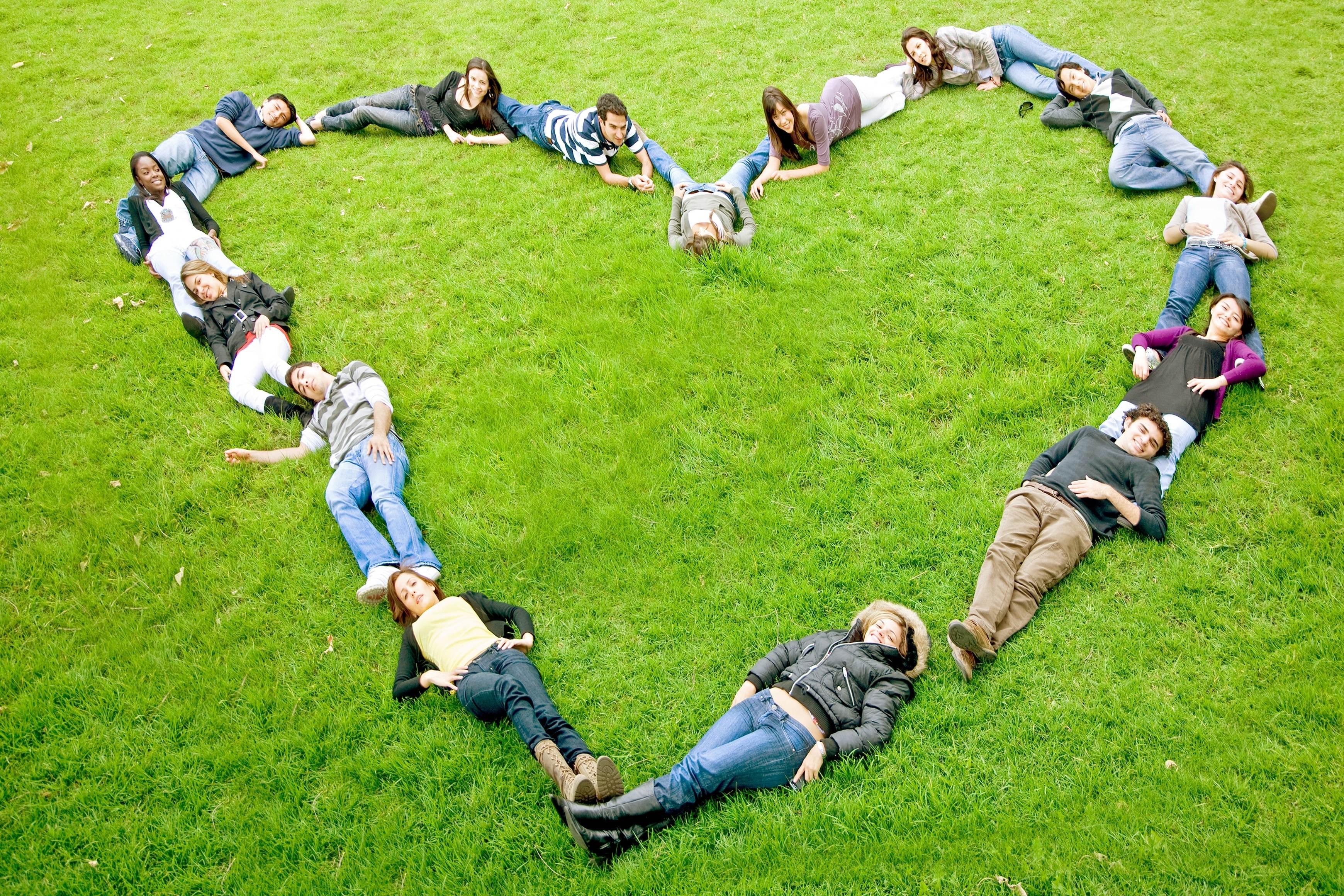 People forming heart shape on grass