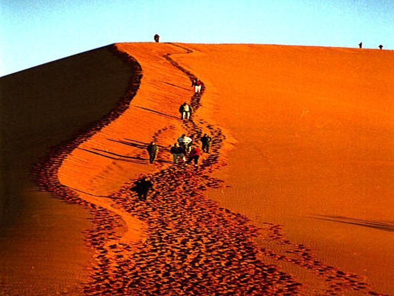 People Hiking on Sand Dune