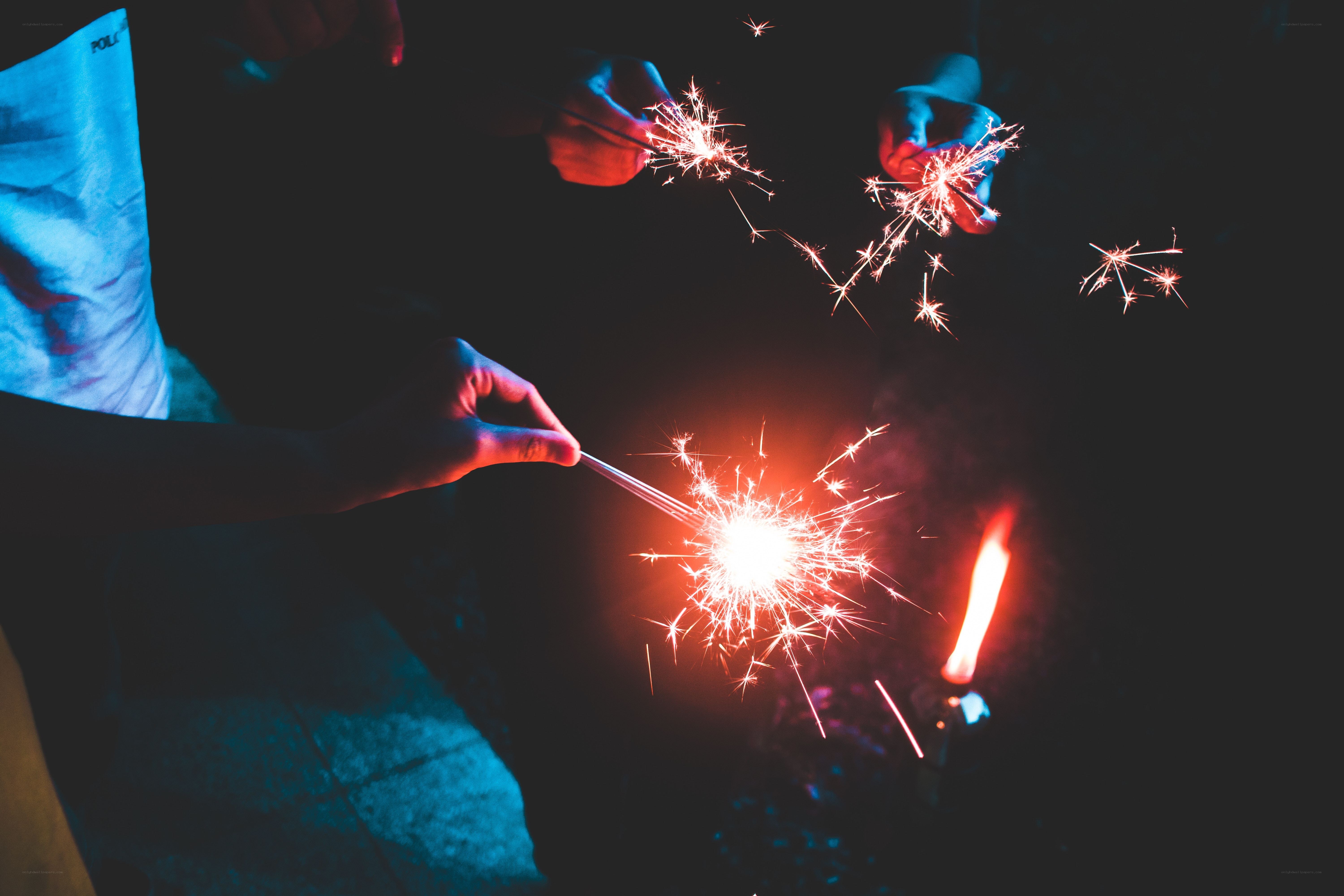 People holding sparklers at night
