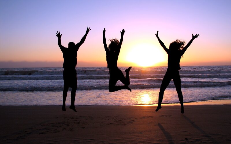 People jumping on the beach at sunset