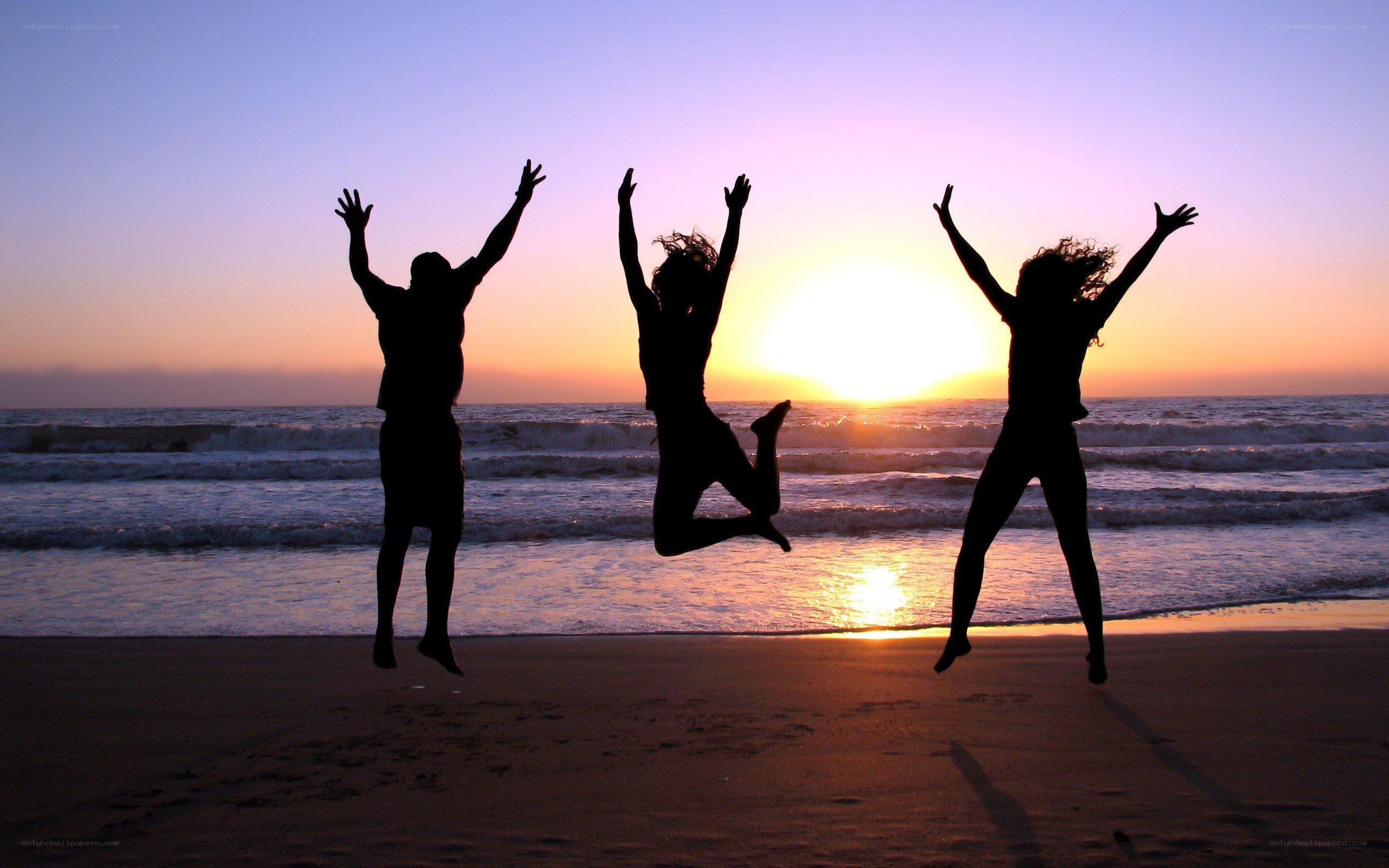 People jumping on the beach at sunset