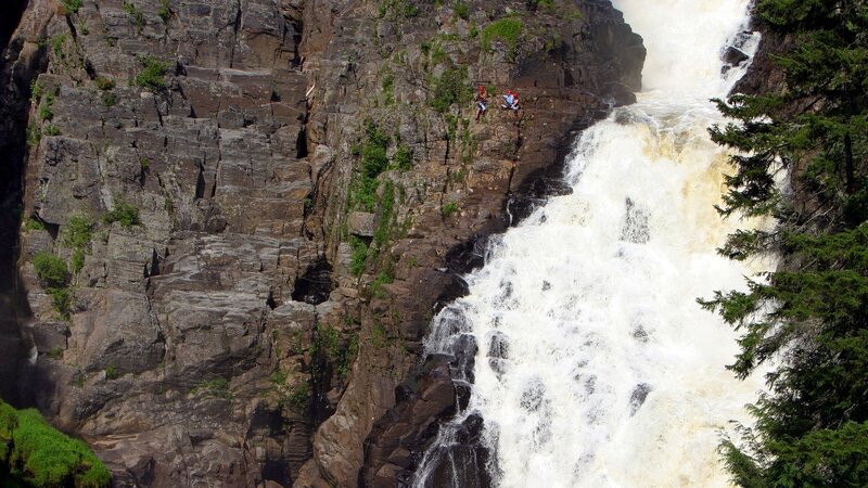 People near a waterfall on a cliff