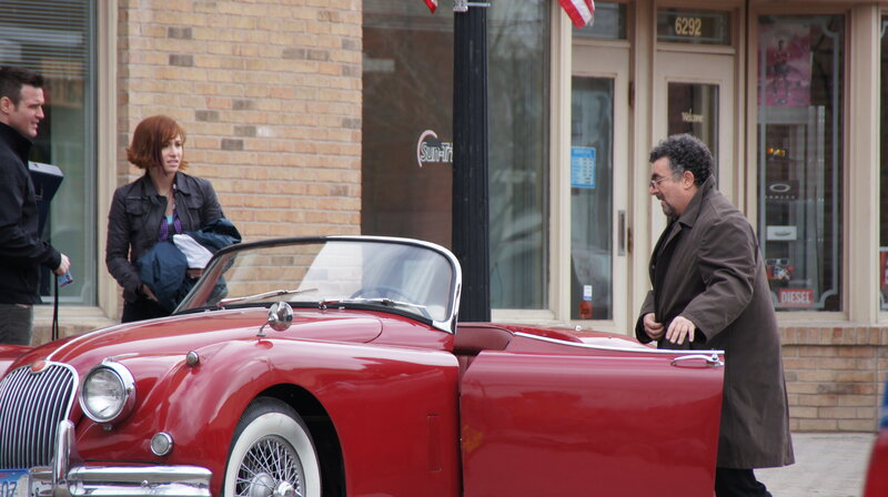 People near red classic car